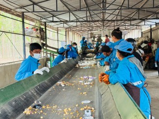 Workers sorting waste on a recycling line, representing environmental aspects and impacts