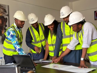 Engineers in hard hats and high-visibility vests reviewing plans, representing OHSAS 18001 history